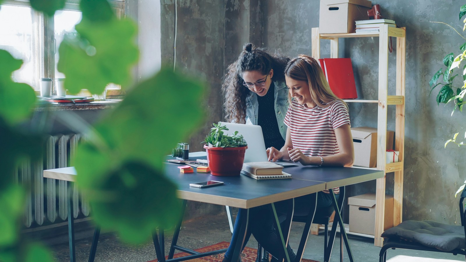 Two colleagues collaborating at a desk with a laptop